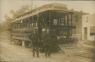 Historic black and white photo of street car trolley with conductors standing in front