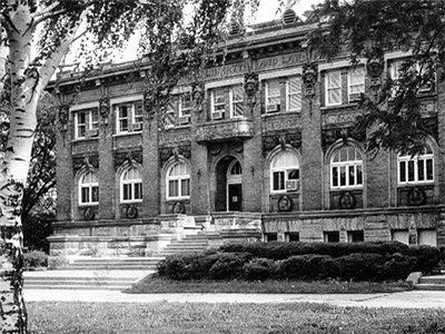 Black and white photo view of KCKPL Carnegie Building framed through trees, circa 1960