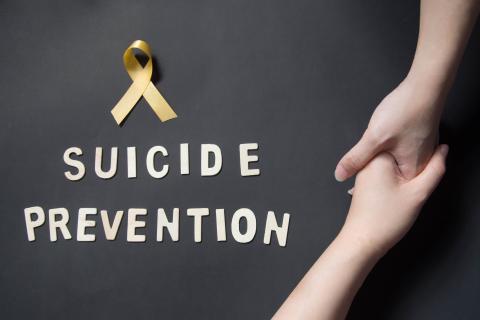 Two hands with suicide prevention written beside them and a yellow ribbon