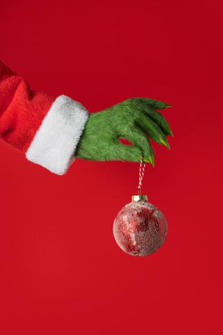 green furry grinch hand holding ornament. 