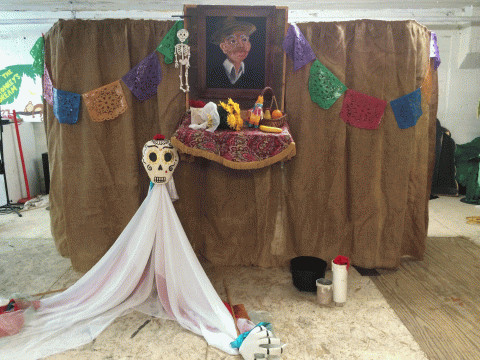 Photo of the stage for the puppet show featuring a skull and papel picado decorations. 