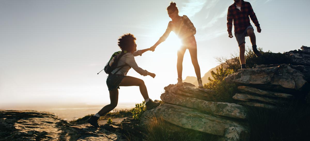 hikers helping each other up a hill