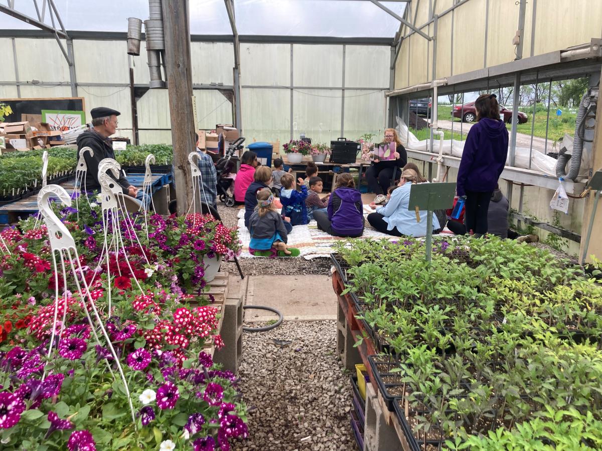 Librarian reading to children inside a greenhouse