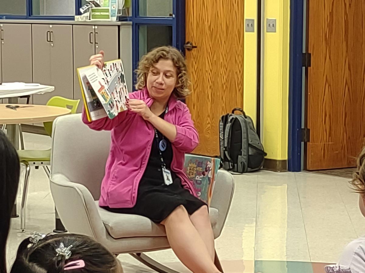 Woman sits in rocking chair reading a picture book