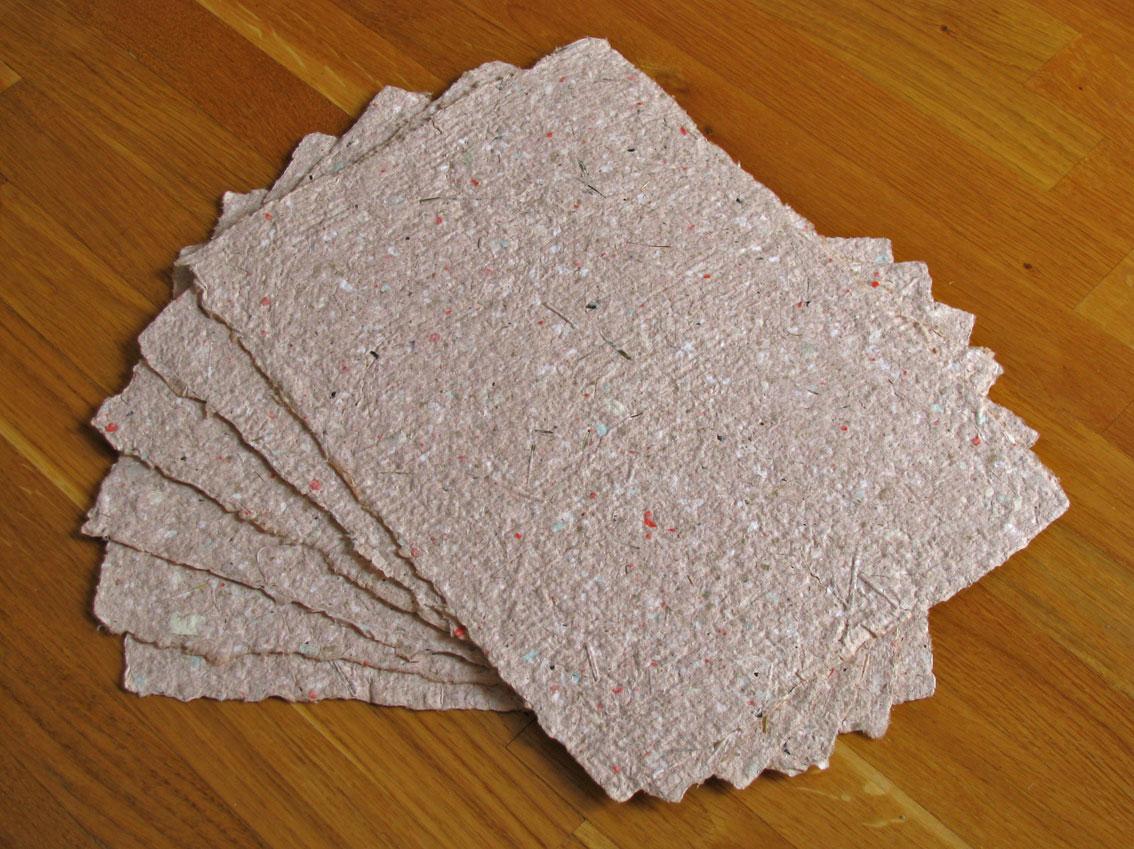 Homemade paper is stacked on a desk. 