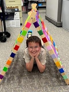 Boy under reading tent made out of duct tape and wood.