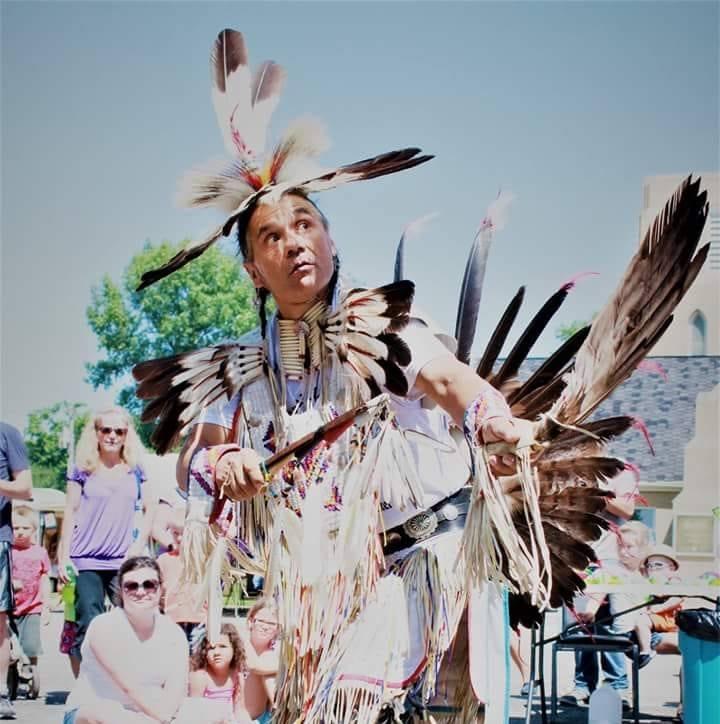 Dennis Rogers dressed in Dine Regalia looking at the sky, while dancing outdoors. 